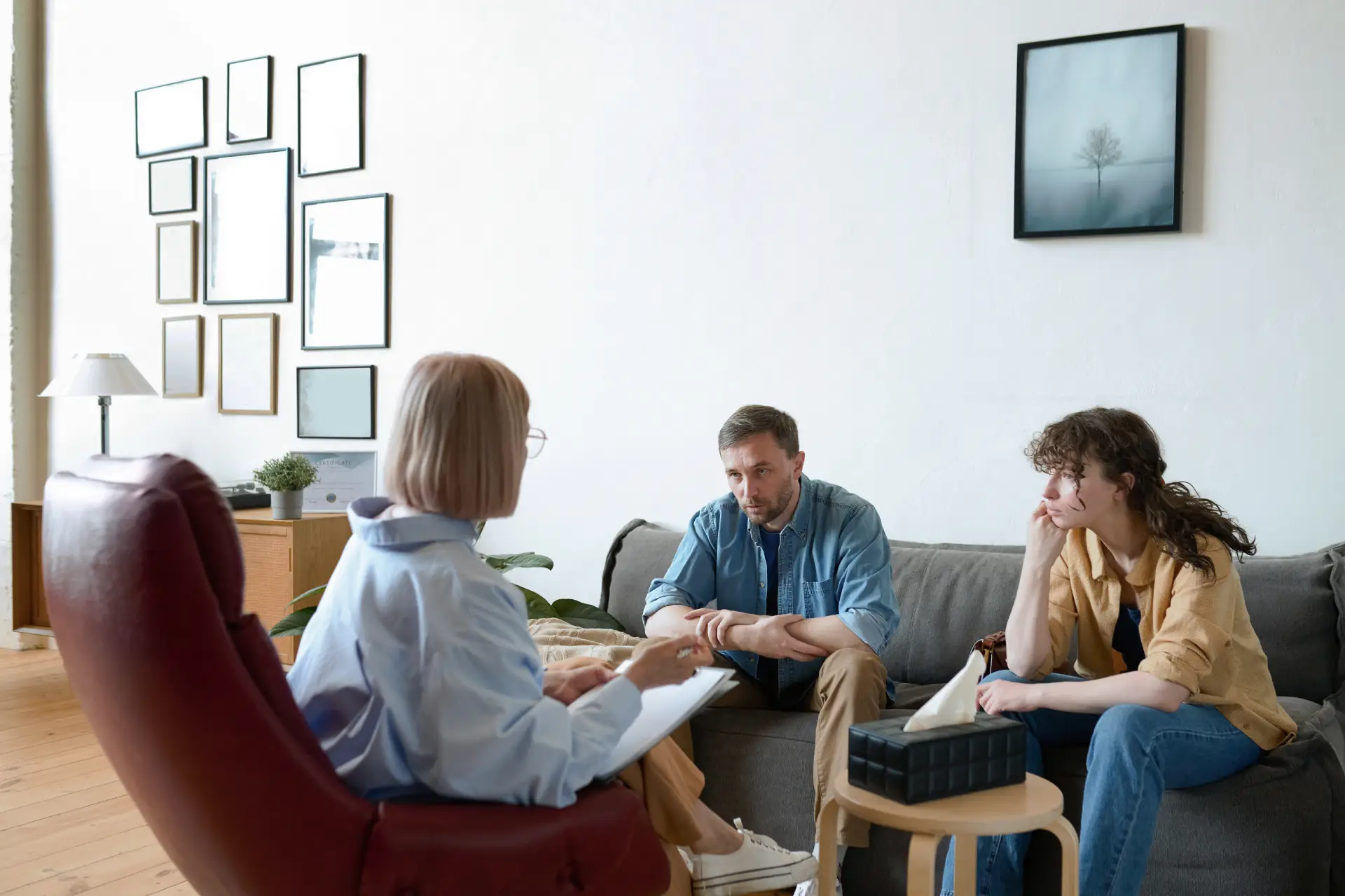 A family counseling session in progress, showing a therapist with a client and their loved one, emphasizing support systems.